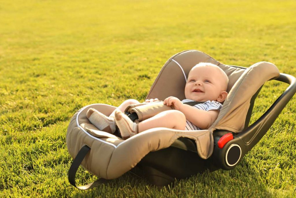 zlaté dieťa v detskej autosedačke na zelenej tráve